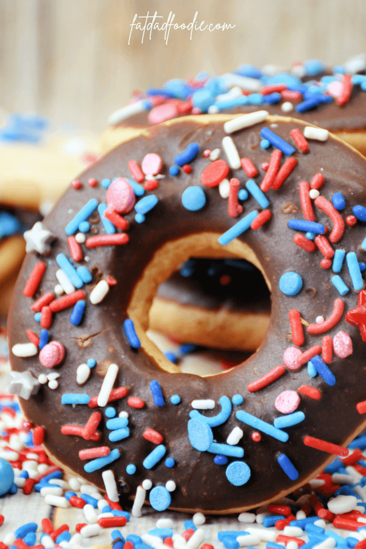 Cookie shaped donut with chocolate frosting and red, white, and blue sprinkles.