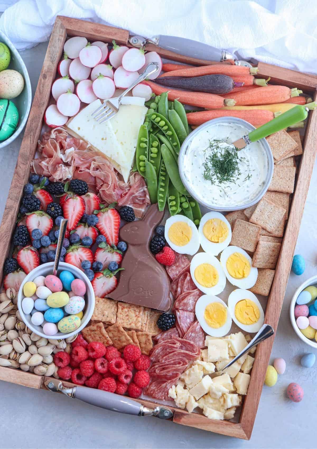 Easter grazing platter with crackers, fruits, veggies, dip, chocolate, and deviled eggs