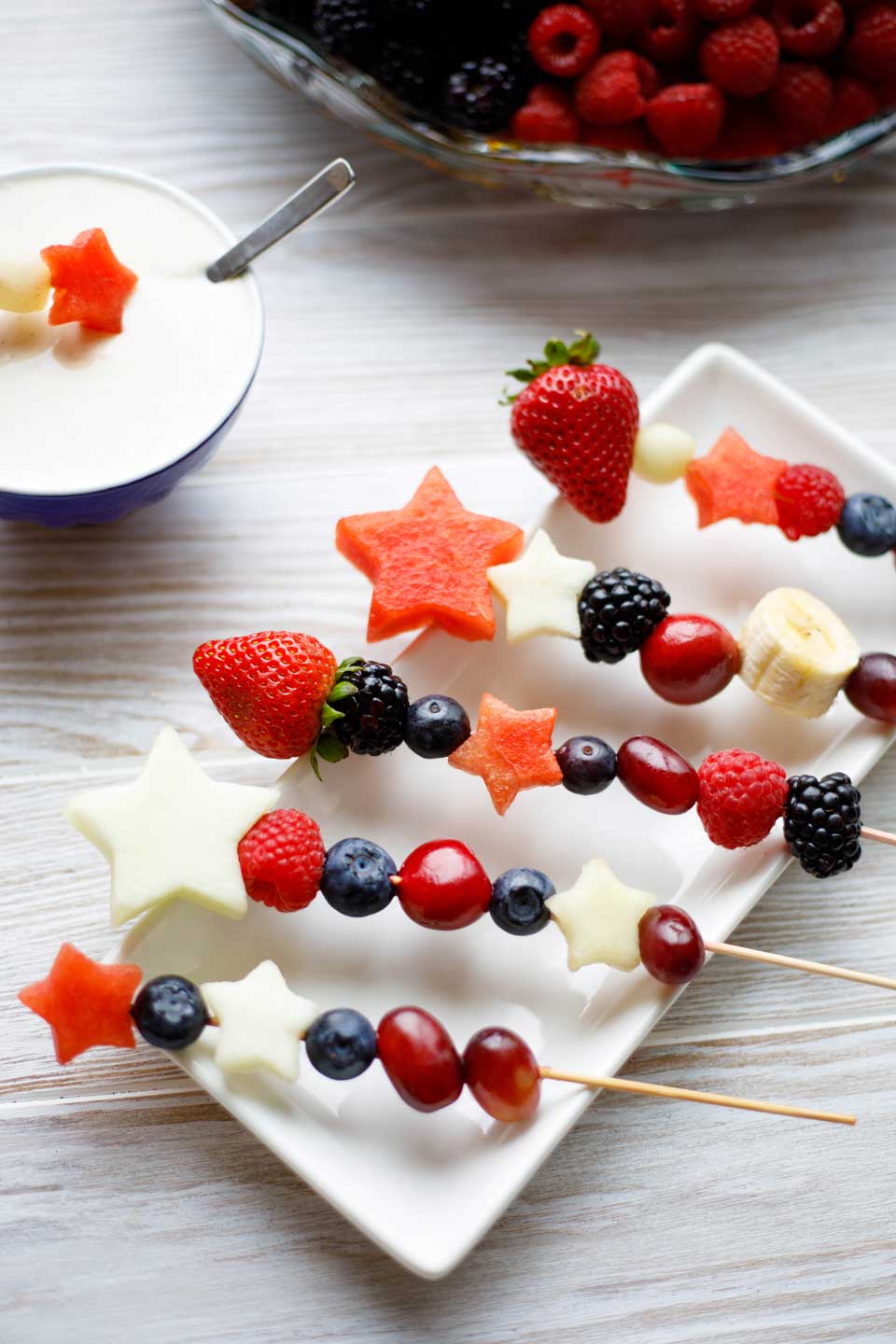 Red, White and Blue Fruit Kabobs on a white plate with fruit dip 