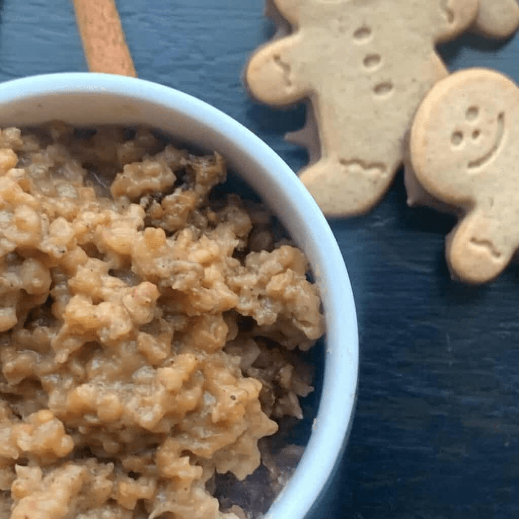 Lazy gingerbread cookie overnight oatmeal in a bowl next to gingerbread men