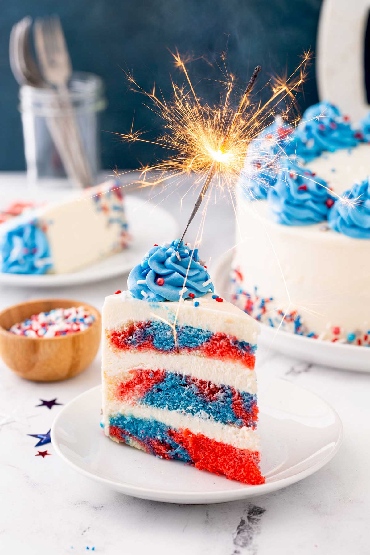 Red white and blue marble layered cake with a lit sparkler on top
