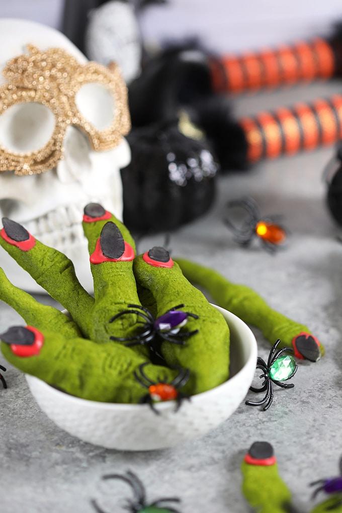 Green witch finger shortbread cookies with black fingernails and fake spider rings on them