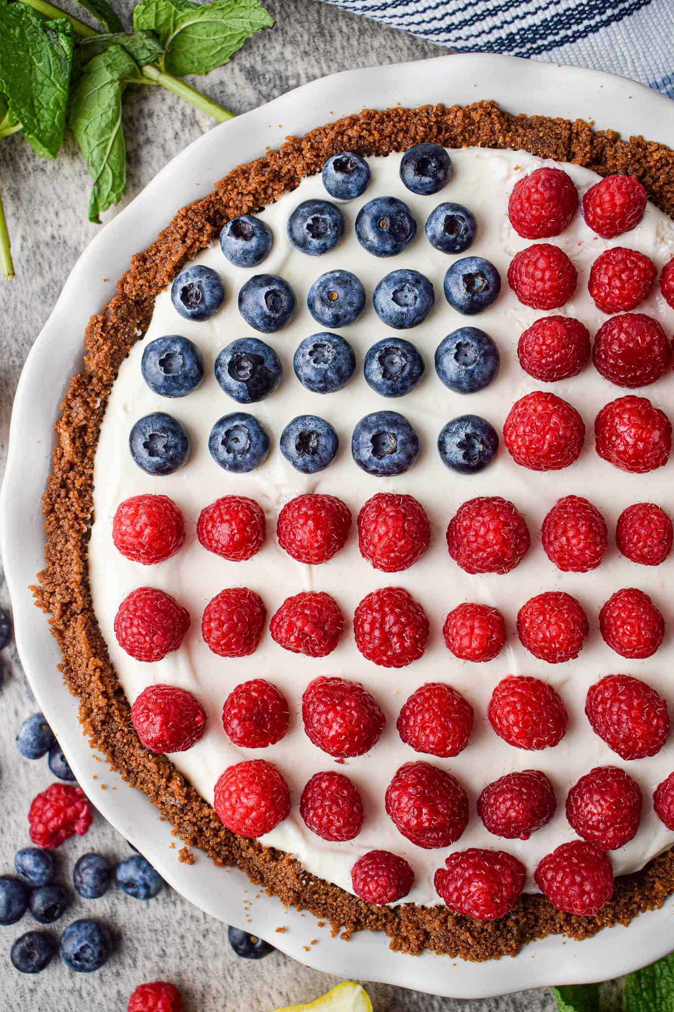 4th of July no bake pie with a graham cracker crust. The filling is white and the toppings are blueberries and raspberries, making it look like an American flag.