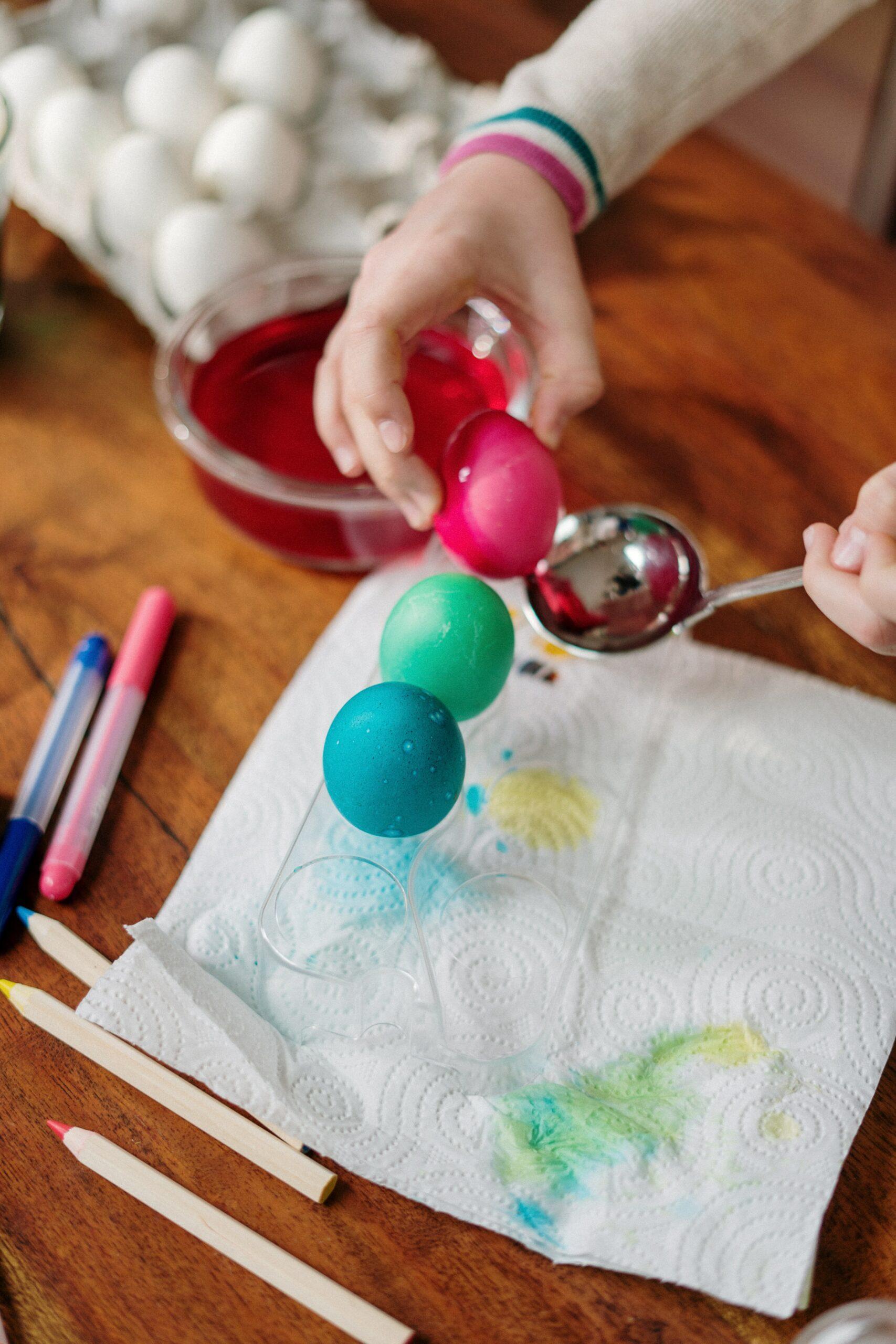 Dyeing Easter eggs with pink, green, and blue colors.