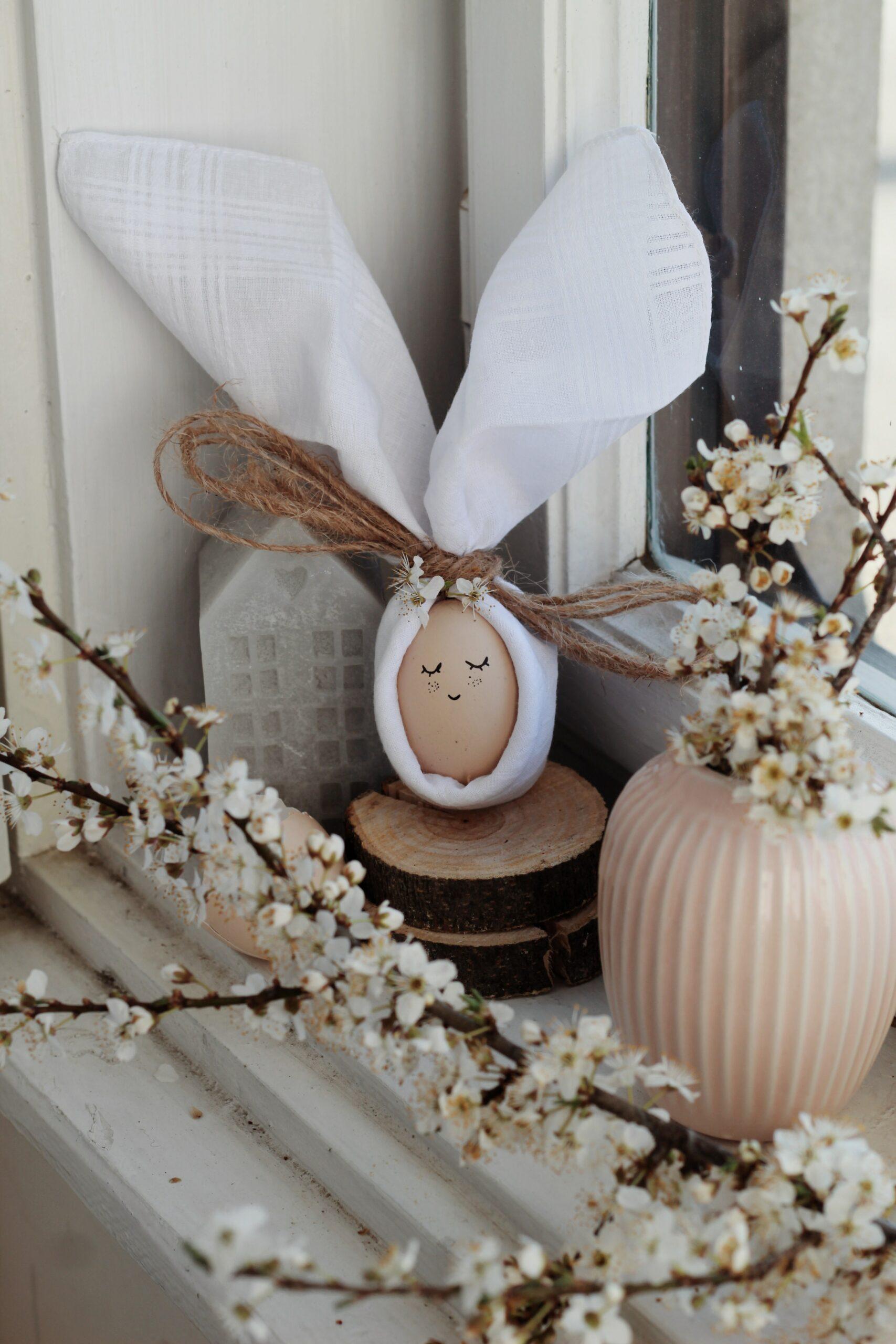 A brown egg with a little face drawn on it. It is wrapped in a white cloth and tied at the top to look like an Easter bunny