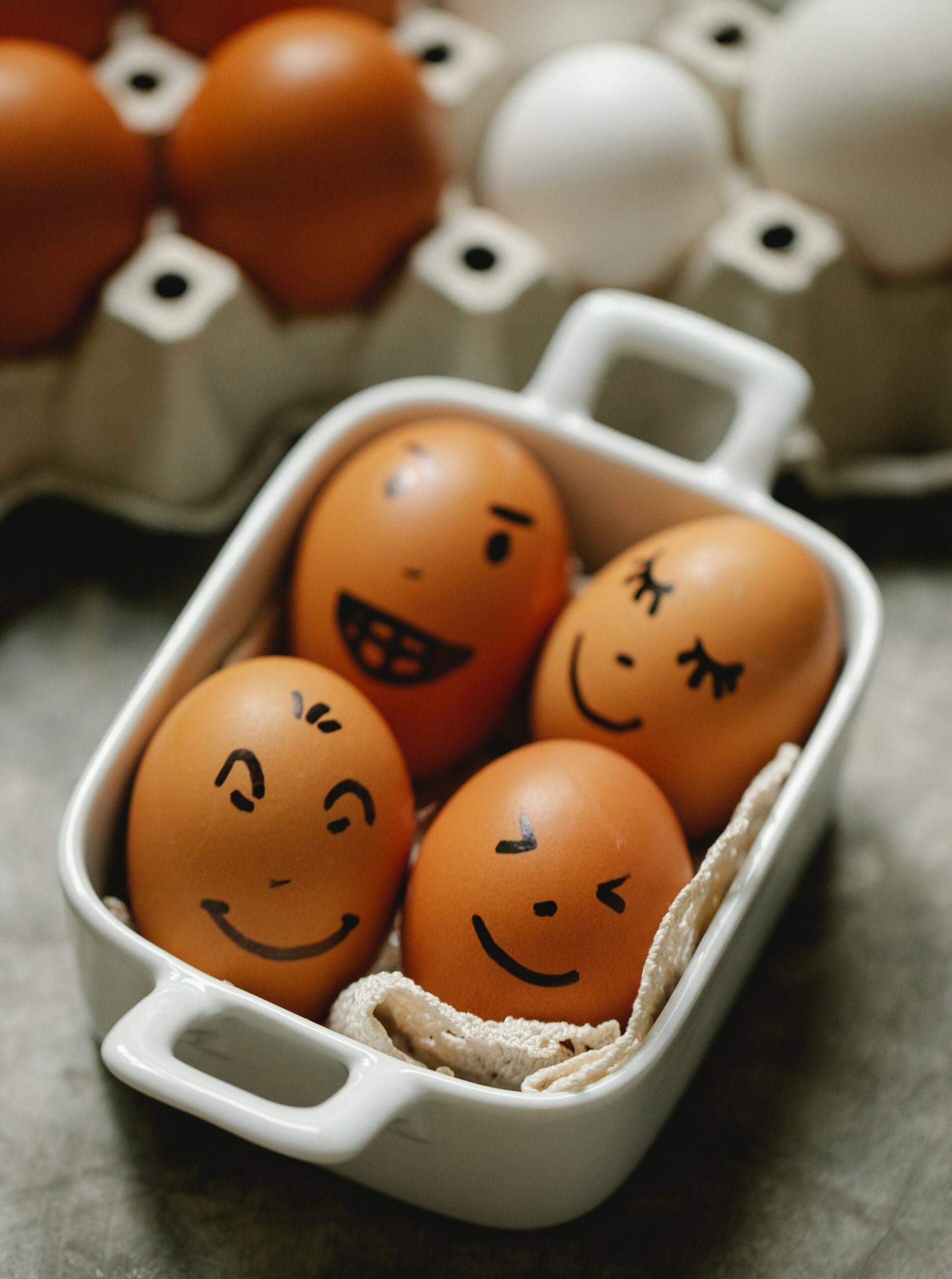 Four brown eggs with faces drawn on them. They are all smiling but have different types of faces