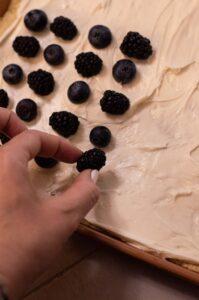 Easy 4th of July Fruit Pizza being made with berries