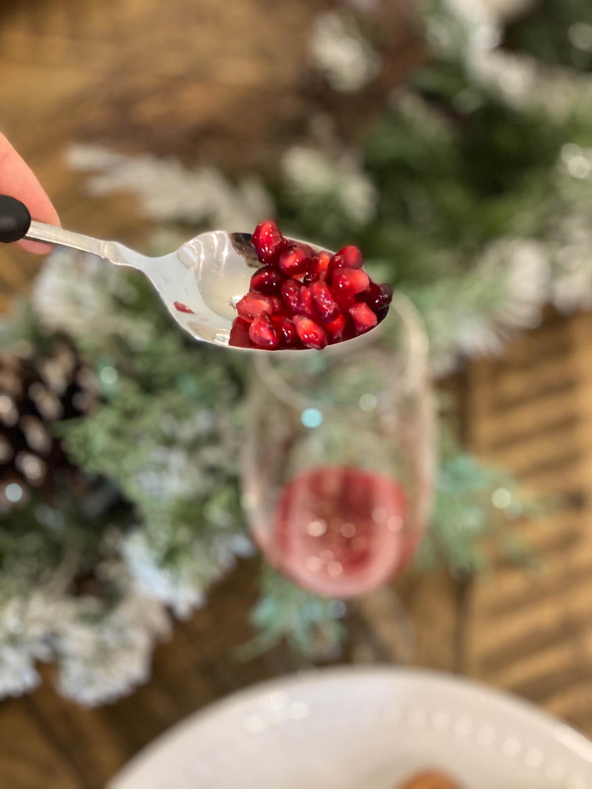 Cranberry arils on a spoon going into a glass