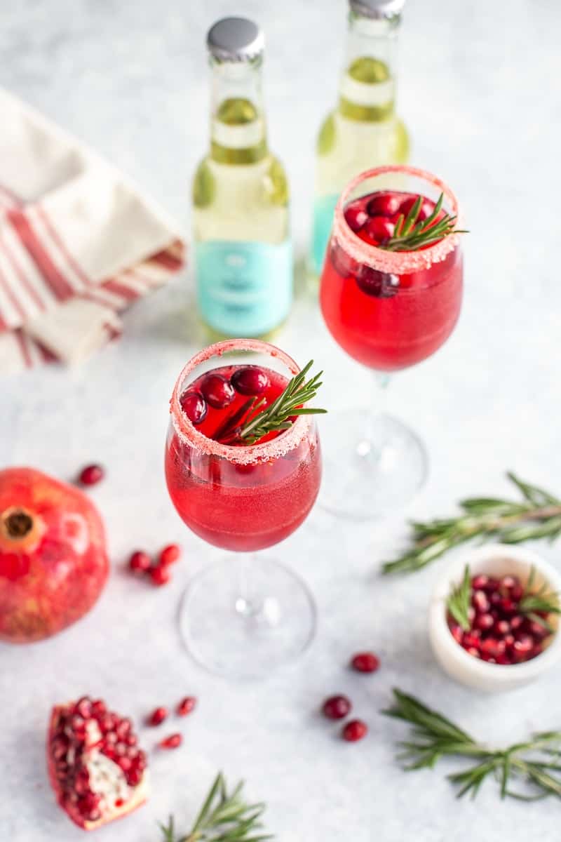 Non-alcoholic champagne drink in glasses with cranberries, pomegranate and rosemary