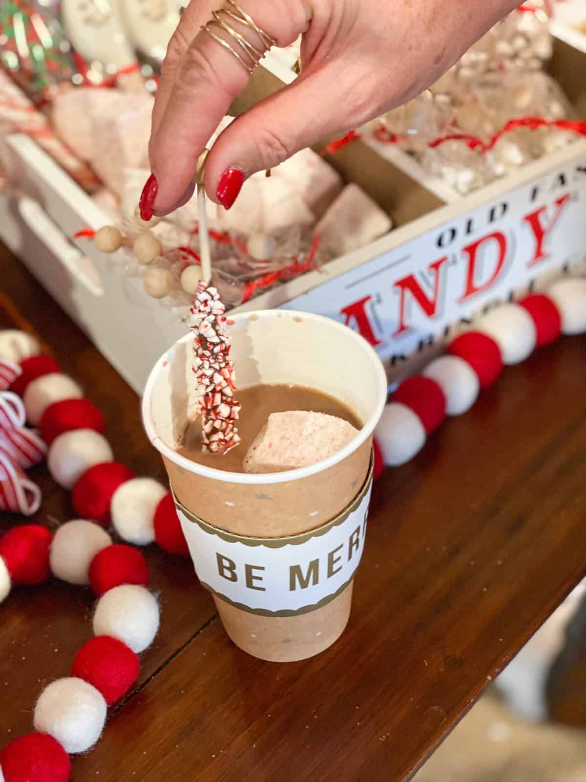 Peppermint covered chocolate stick being dipped into hot cocoa