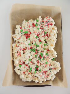 Easy Christmas Popcorn with sprinkles on a parchment lined baking sheet