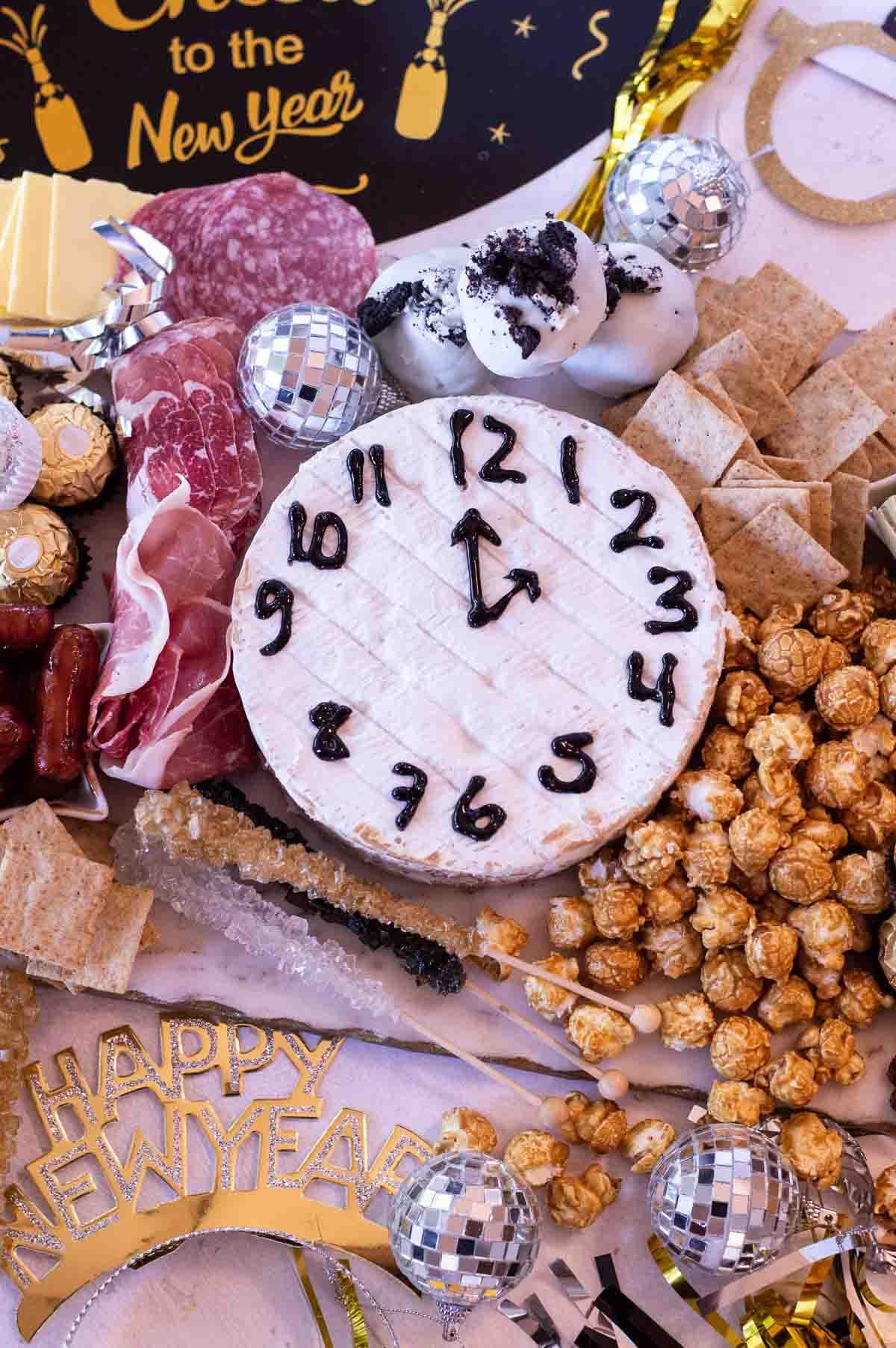New Year's Eve Charcuterie Board with treats and a brie clock