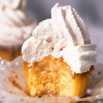 Square image of champagne cupcakes with vanilla frosting and lit candle on top