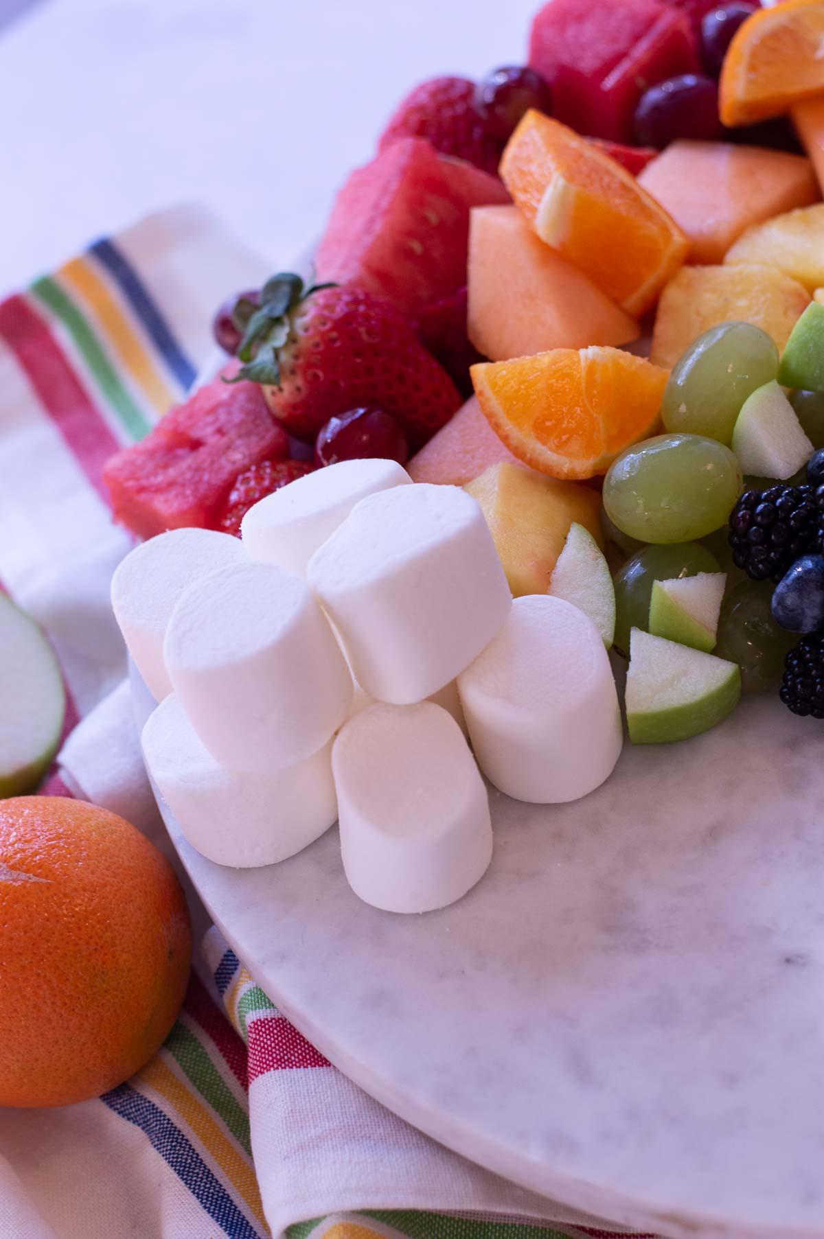 Rainbow Fruit Platter on a marble board with marshmallows for clouds