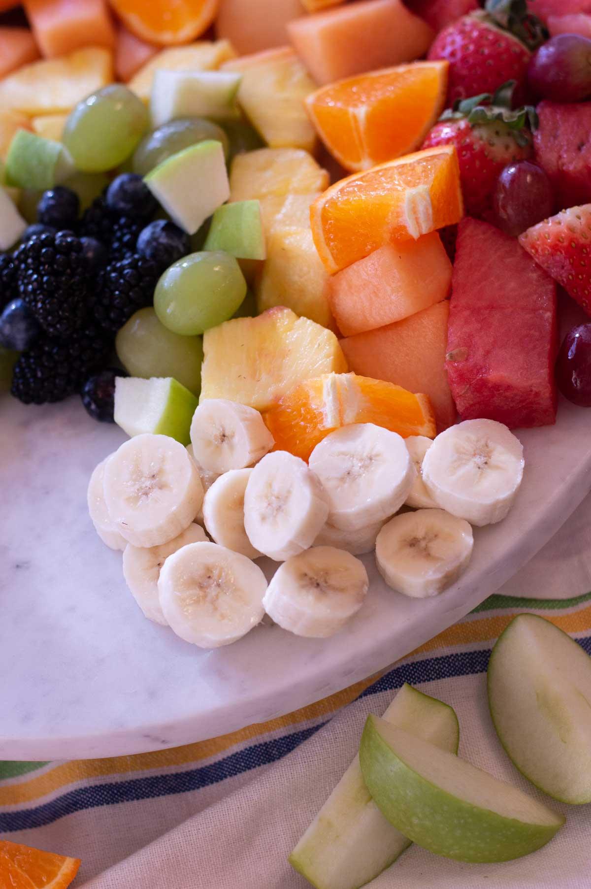 Rainbow Fruit Platter on a marble board with banana slices for clouds