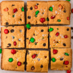 Christmas cookie bars cut into squares with a golden brown top and red and green sprinkles