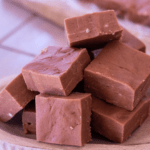 squares of chocolate velveta fudge stacked onto a plate from the side view to show texture.