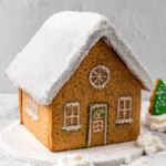 Square image of gingerbread house with gingerbread house frosting on the roof, door, windows