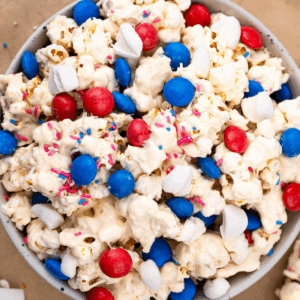 white bowl filled with 4th of july popcorn with white chocolate and red white and blue M&ms.
