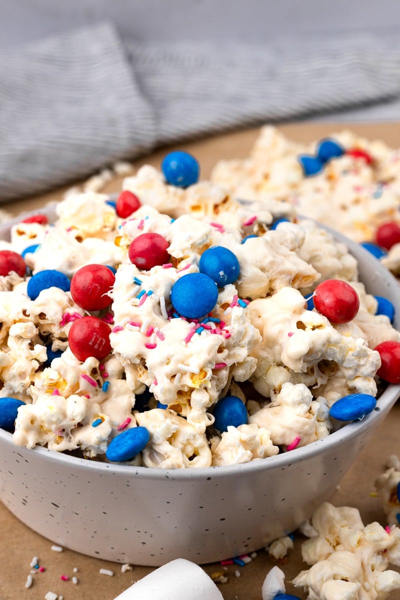 white bowl filled with 4th of july popcorn with white chocolate and red white and blue M&ms.